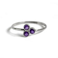 Silver ring with three purple gemstones on a white background