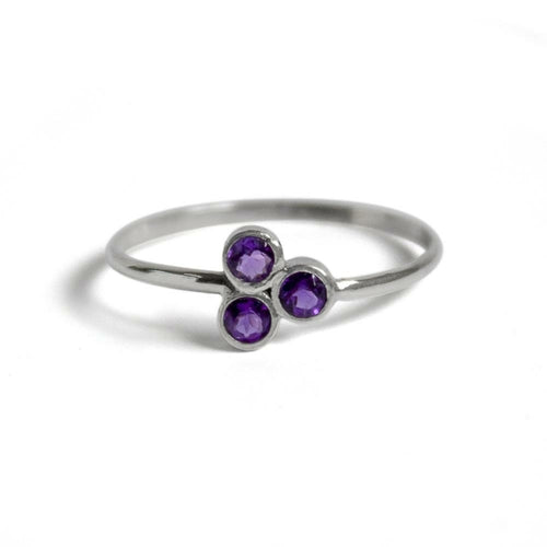 Silver ring with three purple gemstones on a white background