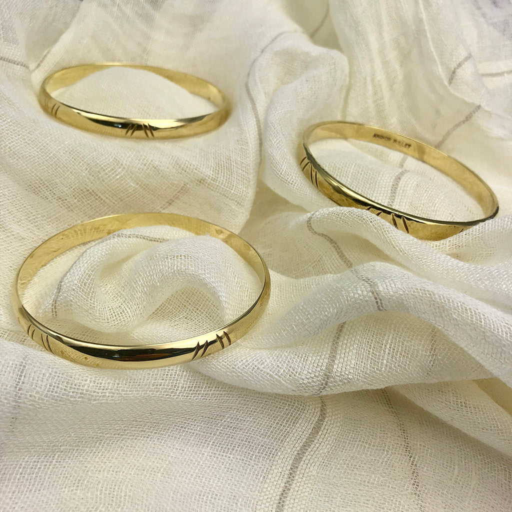 Three gold rings on a textured white fabric background